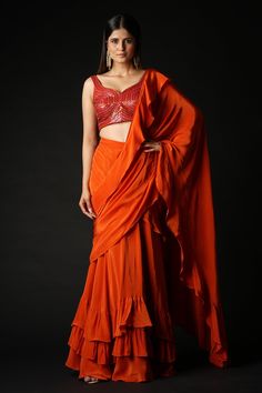 Rust pre-draped saree in a ruffled silhouette. Comes with linear pattern sequin, padded blouse.
Components: 2
Pattern: Embroidered
Type Of Work: Sequin
Neckline: Sweetheart
Sleeve Type: Sleeveless
Fabric: Viscose
Color: Orange
Other Details: 
Saree:
Pre-draped
Tiered ruffles
Blouse:
Attached padding
Back plunged V-neck
Occasion: Destination Wedding,Mehendi and Haldi - Aza Fashions Fitted Pre-draped Saree With Ruffles For Designer Wear, Silk Party Saree With Ruffles, Silk Pre-draped Saree With Ruffles For Party, Silk Blouse Piece With Ruffles For Reception, Silk Pre-draped Party Saree With Ruffles, Silk Party Pre-draped Saree With Ruffles, Silk Ruffled Blouse Piece For Reception, Designer Silk Lehenga With Ruffles, Festive Silk Lehenga With Ruffles