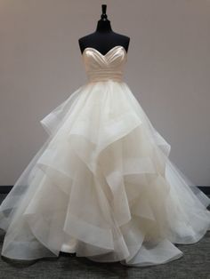 a white wedding dress on a mannequin with ruffles around the skirt