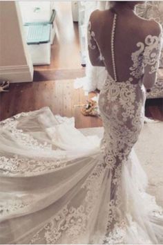 the back of a wedding dress with white lace and flowers on it, as seen from behind