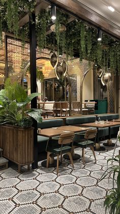 a restaurant with tables, chairs and plants hanging from the ceiling