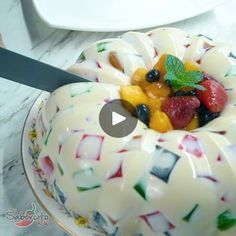 a white cake with fruit on top sitting on a plate