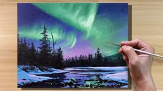 someone is holding a paintbrush and painting an image of the aurora bore in the sky