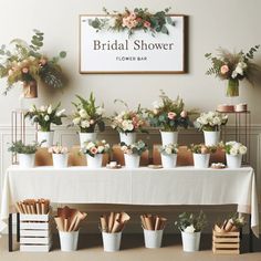 a table topped with lots of potted plants next to a sign that says bridal shower