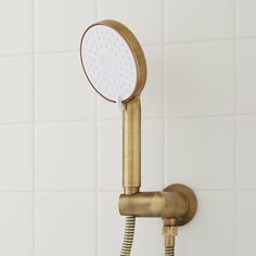 a gold shower head with thermostaer attached to it's side in a white tiled bathroom