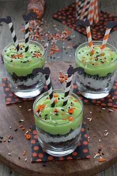 three glasses filled with green liquid and sprinkles on top of a wooden tray