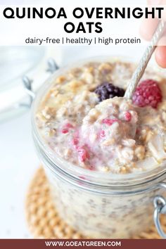 a hand is holding a spoon over a bowl of oatmeal with berries