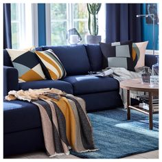 a living room with blue couches and colorful throw pillows on the rugs in front of it