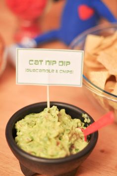 a bowl of guacamole and chips with a sign that says cat nip dip