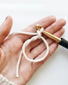 a person holding a pen in their hand with a knot on the end of it