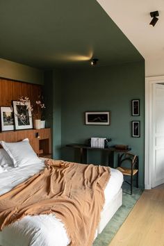 a bedroom with a bed, desk and pictures on the wall above it's headboard