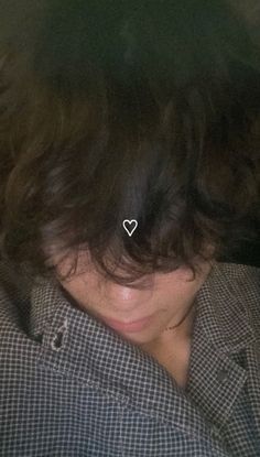 a close up of a person wearing a shirt with a heart pin in their hair