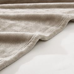 a close up view of a blanket on a bed with white sheets and pillow cases