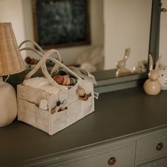 an empty bag sitting on top of a dresser next to a lamp and other items