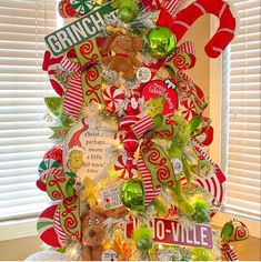 a christmas tree decorated with candy canes and candies is displayed in front of a window