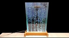 a wooden table with a glass vase on top of it and a black background behind it