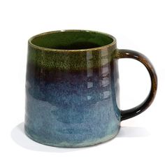 a blue and green coffee mug sitting on top of a table