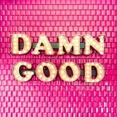 the words damn good are lit up against a pink background