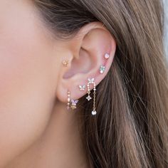 a close up of a woman's ear wearing gold and white flowered earrings