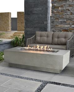 a fire pit sitting on top of a stone floor next to a couch and table