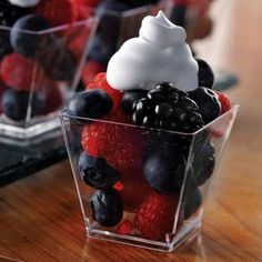 berries, raspberries and blueberries in a plastic container on a wooden table