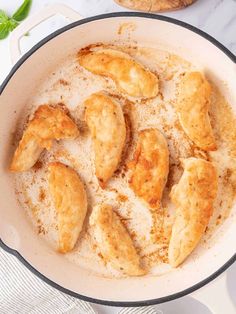 some fried chicken pieces are in a pan on the stove top next to garlic bread