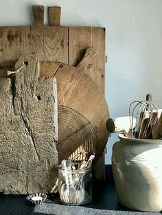 an old wooden cutting board sitting on top of a counter next to other kitchen utensils