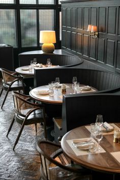 tables and chairs are set up in the corner of a restaurant with black paneled walls