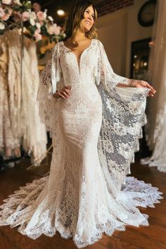 a woman in a white wedding dress standing on a wooden floor with her arms out