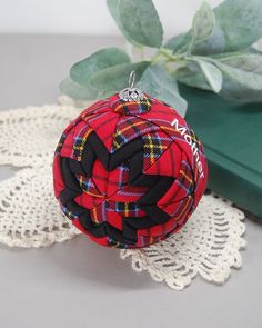 a red and black plaid ball ornament sitting on top of a doily