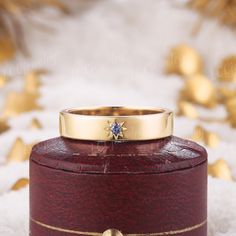 a gold ring sitting on top of a wooden box with snow in front of it