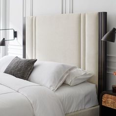 a bed with white sheets and pillows in a bedroom