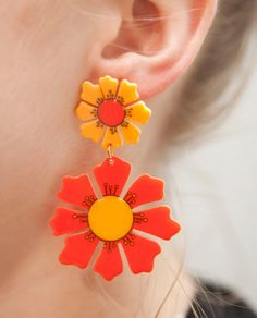 Elevate your style with these stunning 70s Orange Blooms Flower Earrings. Inspired by the vibrant fashion of the 70s, these earrings feature a captivating design that combines retro charm with a modern twist. The bold orange blooms add a pop of color to your look and make a statement wherever you go. Made from super lightweight acrylic material, these earrings ensure comfortable wear throughout the day. The stainless steel posts coated in 18k gold provide durability and a touch of elegance. Embr Boho Jewlery, 70s Accessories, 70s Orange, 70s Jewelry, Vibrant Fashion, 70s Aesthetic, Diy Perler Bead Crafts, Diy Perler Beads, Iconic Fashion