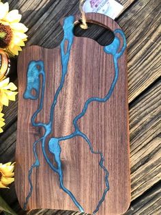 a wooden cutting board with blue paint on it and sunflowers in the background