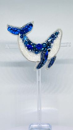 a glass figurine with blue and white designs on it's body, sitting on a clear stand