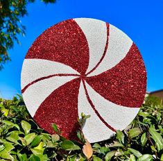 a red and white candy cane sitting on top of green bushes