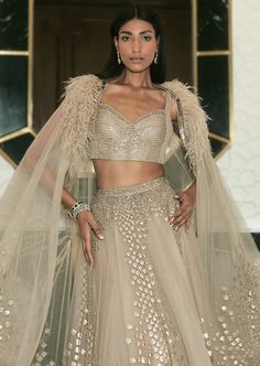 Our Eden lehenga fully embellished with delicate embroideries. Paired up with asymmetric embellished cape. Glamorous Dresses With Intricate Embroidery And Traditional Drape, Glamorous Dresses With Intricate Embroidery, Evening Party Wear Hand Embellished Dupatta, Glamorous Hand Embellished Choli With Traditional Drape, Bollywood Style Gown With Cape Sleeves, Glamorous Designer Dresses With Dupatta, Glamorous Evening Sets With Dupatta, Glamorous Festive Sets With Cape Sleeves, Glamorous Designer Lehenga With Sheer Dupatta