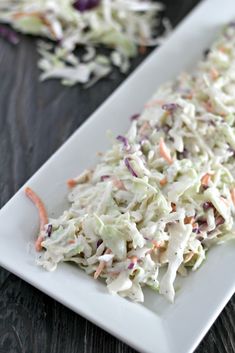 a white plate topped with coleslaw on top of a wooden table