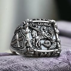 Celebrate the valor and faith of Saint George with our Saint George the Victorious Knight Cross Christian Signet, crafted from high-quality 925 sterling silver. This exquisite ring features a detailed depiction of Saint George, the patron saint known for his legendary battle against the dragon, symbolizing the triumph of good over evil. The cross motif represents unwavering faith and devotion, making this ring perfect for those who appreciate meaningful and inspirational jewelry. The adjustable Commemorative Silver Stainless Steel Jewelry, Silver Hallmarked Signet Ring For Commemoration, Hallmarked Silver Signet Ring For Commemoration, Commemorative Sterling Silver Rings, Silver Polished Signet Ring For Commemoration, Sterling Silver Jewelry With Engraving For Commemoration, Silver Signet Ring With Polished Finish For Commemoration, White Gold Jewelry Stamped 925 For Commemoration, Logger Boots