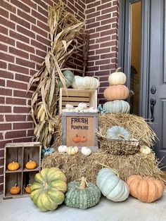 pumpkins and gourds are stacked on hay in front of a brick building