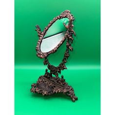 an antique looking mirror on a stand against a green background