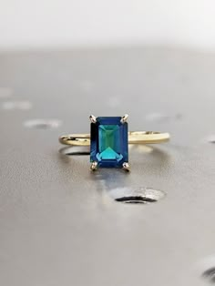 Teal Sapphire Ring Nodeform, Blue Emerald Wedding Ring, Blue Emerald-cut Ring With Birthstone, Blue Emerald Cut Ring, Birthstone, Blue Emerald Cut Ring For Birthstone, Blue Emerald Cut Ring With Birthstone, Blue Emerald Gemstone Ring, Blue Emerald Jewelry With Accent Stones, Elegant Blue Sapphire Ring For May Birthstone