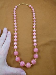 25 inch long faceted round Pink Rhodochrosite gemstone graduated beaded  with gold tone spacers Neck Luxury Necklace With Faceted Round Beads, Luxury Temple Necklace With Polished Round Beads, Luxury Temple Jewelry Beaded Necklace With Round Beads, Luxury Faceted Round Bead Crystal Necklaces, Pink Polished Round Bead Necklaces, Pink Round Polished Bead Necklaces, Vintage Pink Single Strand Jewelry, Vintage Pink Faceted Bead Jewelry, Pink Faceted Round Bead Necklaces