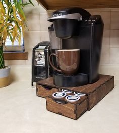 a coffee maker sitting on top of a wooden box next to a cup and saucer