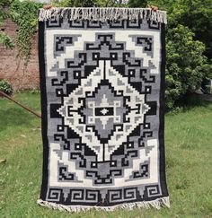 a black and white quilt hanging in the grass