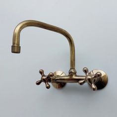 an antique brass faucet with two spouted handles on a gray background