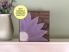 a purple crochet art piece next to a vase with flowers