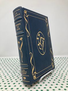 a blue book sitting on top of a white and green tablecloth covered table cloth