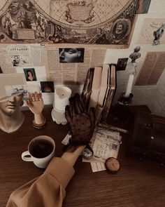 a table topped with lots of books and cups of coffee next to a statue on top of a wooden table