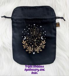 a small black pouch with a gold hand and stars on it sitting on top of a white furnishing