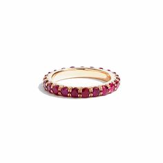 a gold ring with red stones on the inside and outside, set against a white background